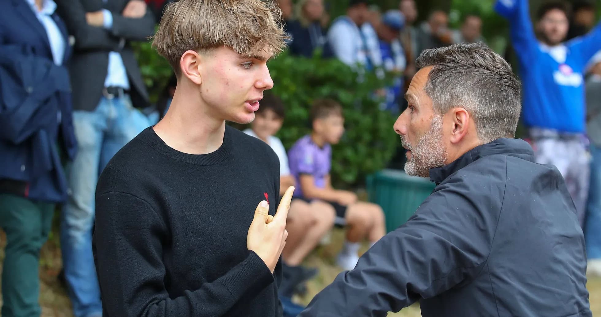 Young man talking to an older man in crowd