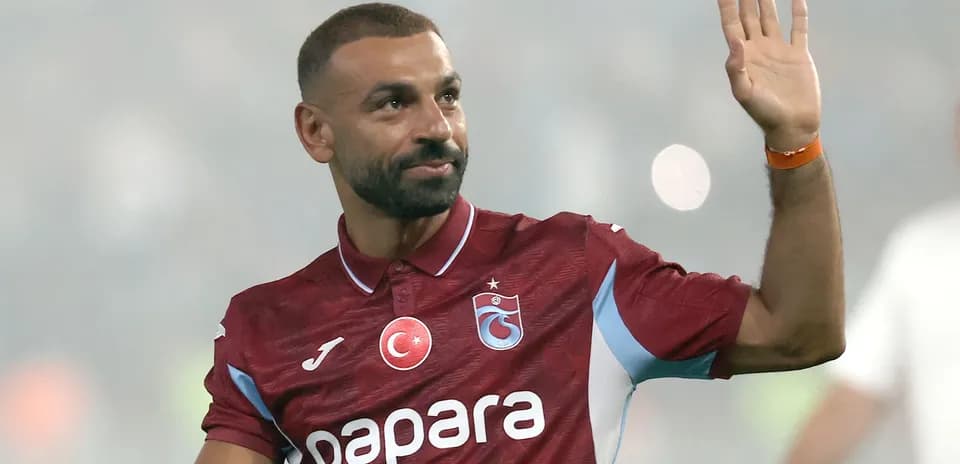Futbolchi jamoaga qo'shilib, qo'l silkitmoqda