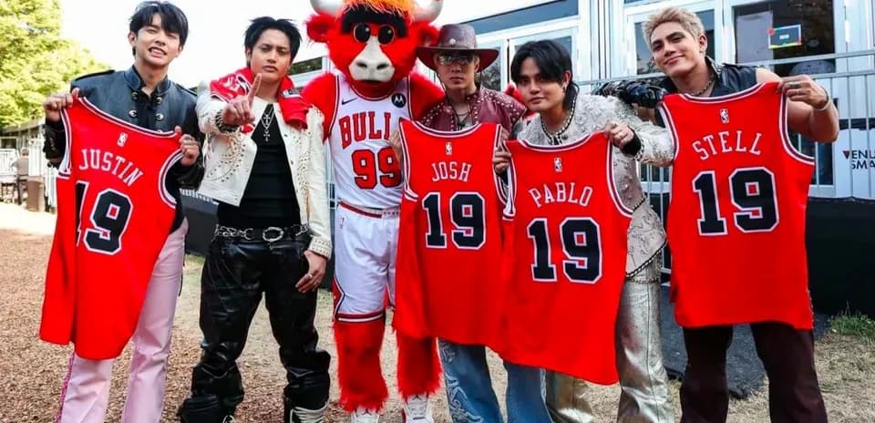 Group of five holding basketball jerseys with mascot