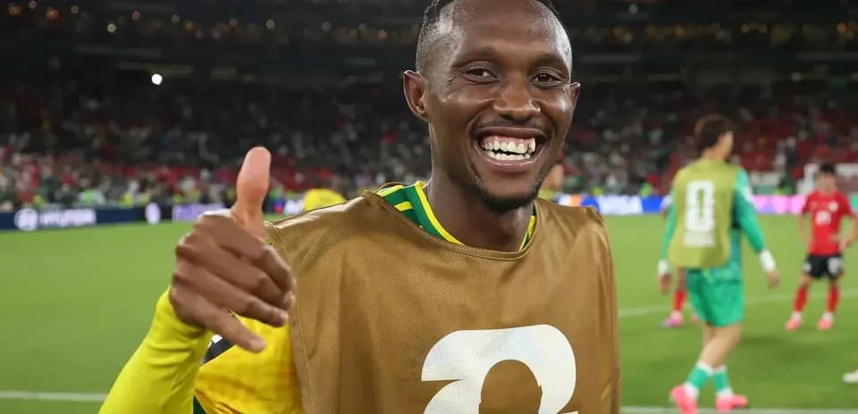 Futbolchi maydonda qo'lini ko'tarib tabassum qilmoqda