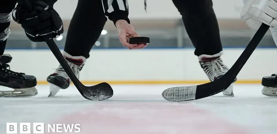 Referee dropping puck for face-off in hockey game