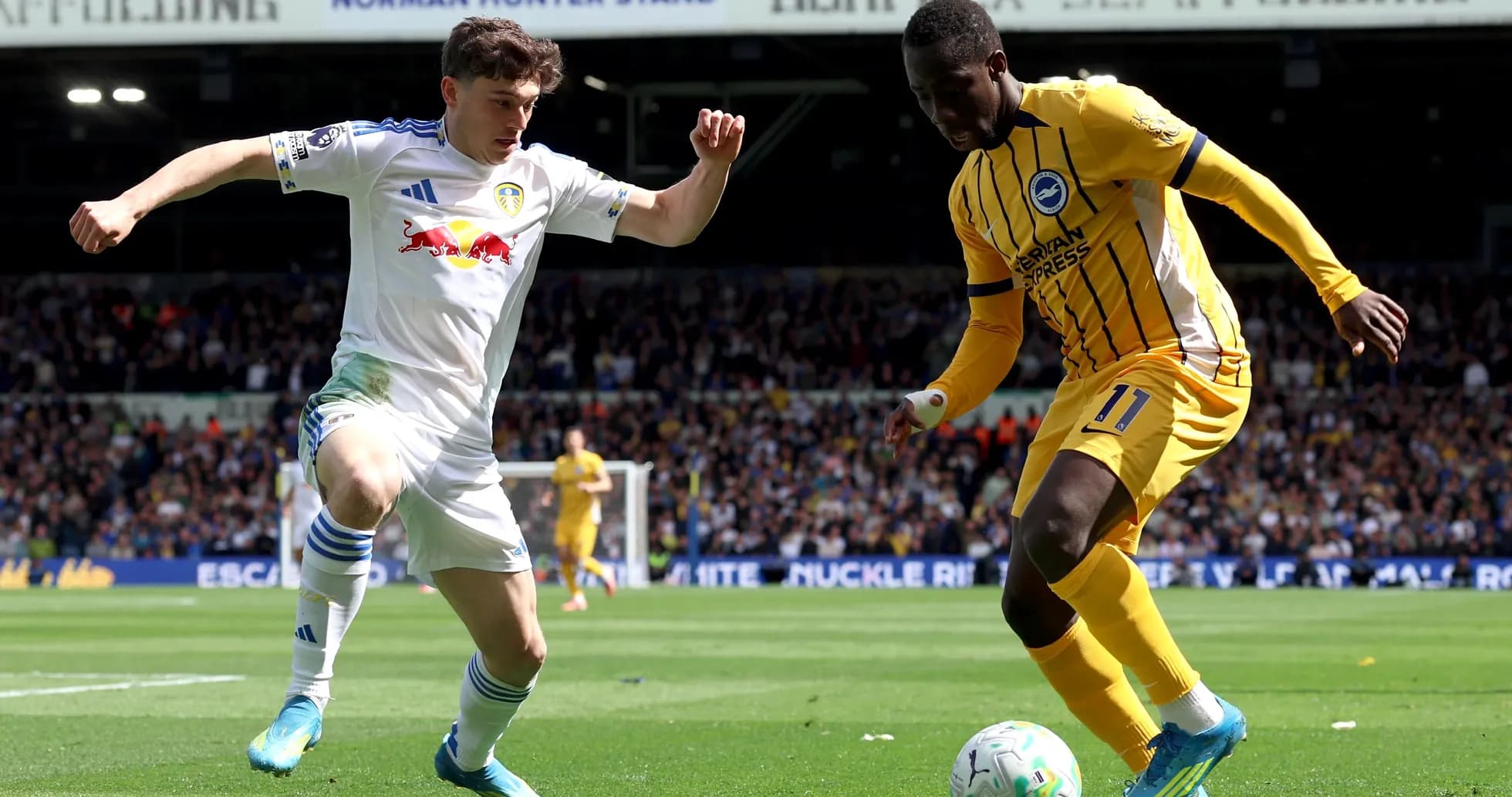 Leeds United player challenging Brighton player for ball