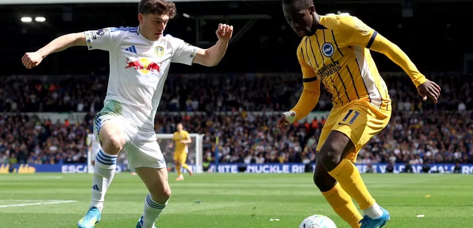 Leeds United player challenging Brighton player for ball