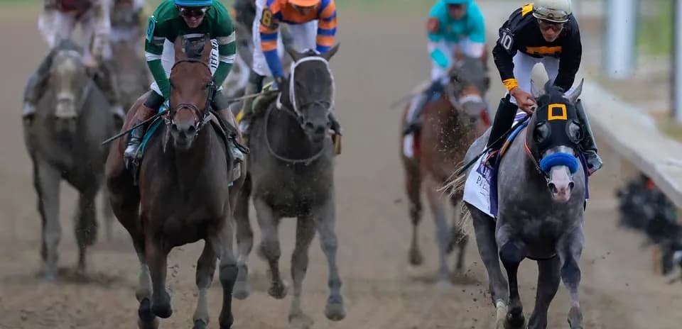 Jockeys racing horses on dirt track during competition