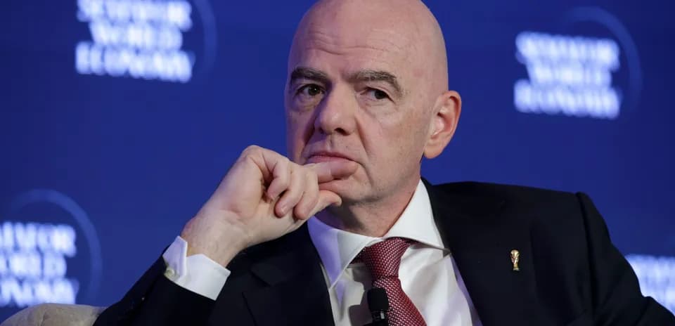 Man speaking at conference with FIFA World Cup pin