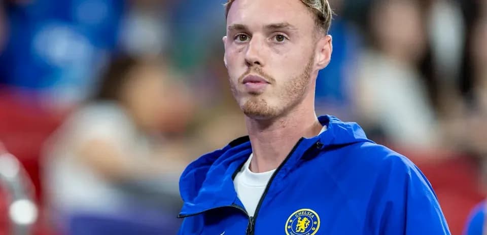 Futbolchi Chelsea formasida, tomoshabinlar oldida turibdi