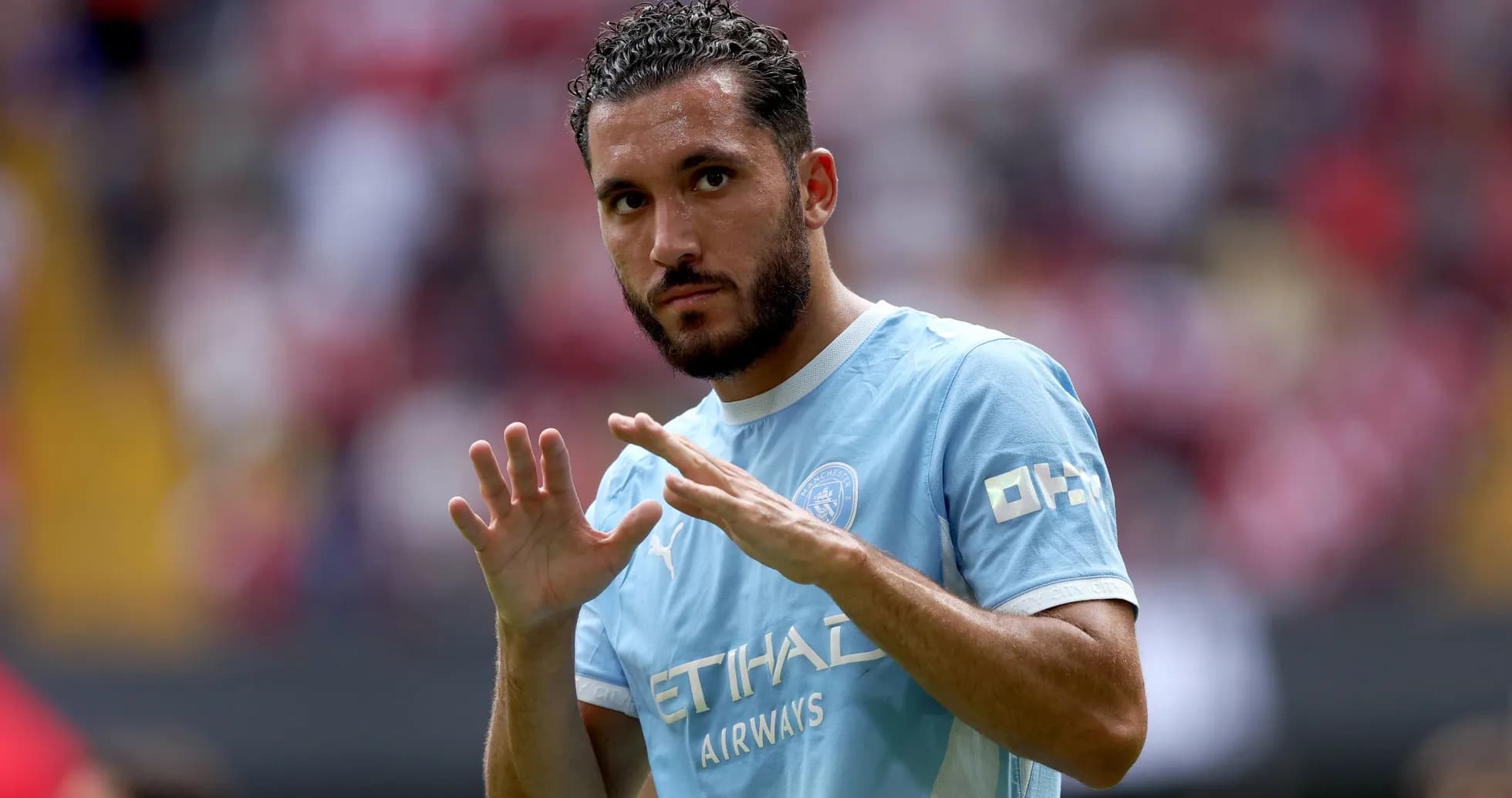 Futbolchi maydonda qo'llarini ko'tarib turibdi