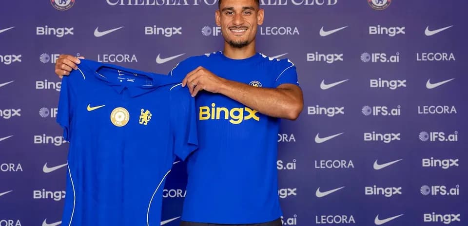 Futbolchi Chelsea futbol formasini ko'rsatmoqda