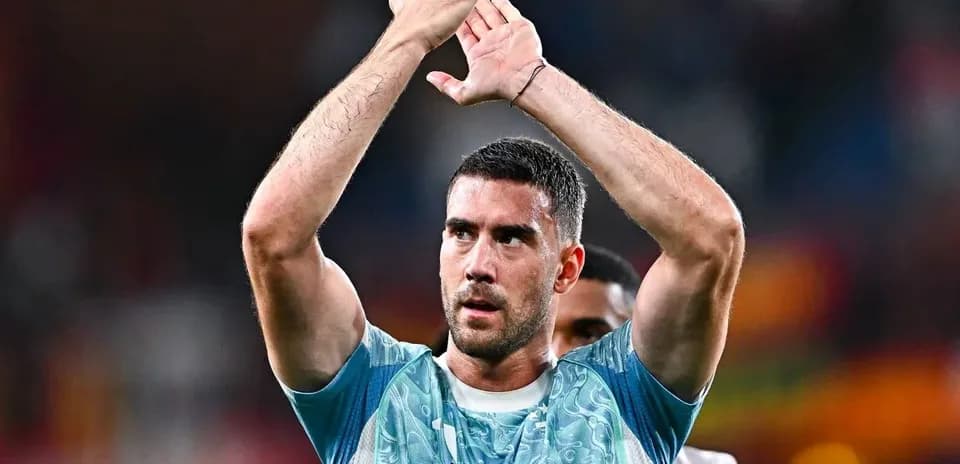 Futbolchi maydonda qo'llarini ko'tarib turibdi
