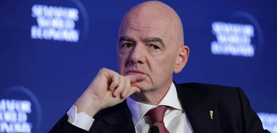 Man speaking at a conference with FIFA emblem