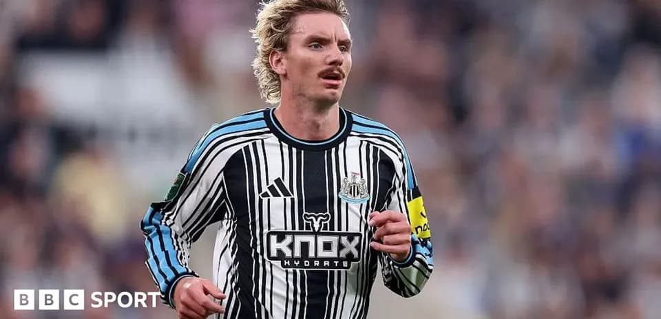 Futbolchi Newcastle formasida maydonda yugurmoqda