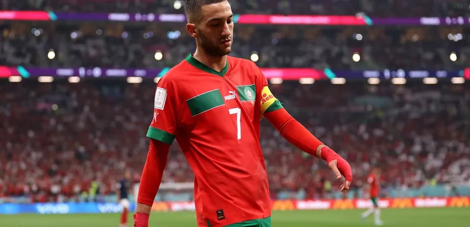 Hakam Ziyech walking on the pitch in red jersey