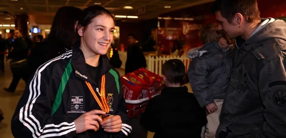 Athlete holding medal at airport with fans