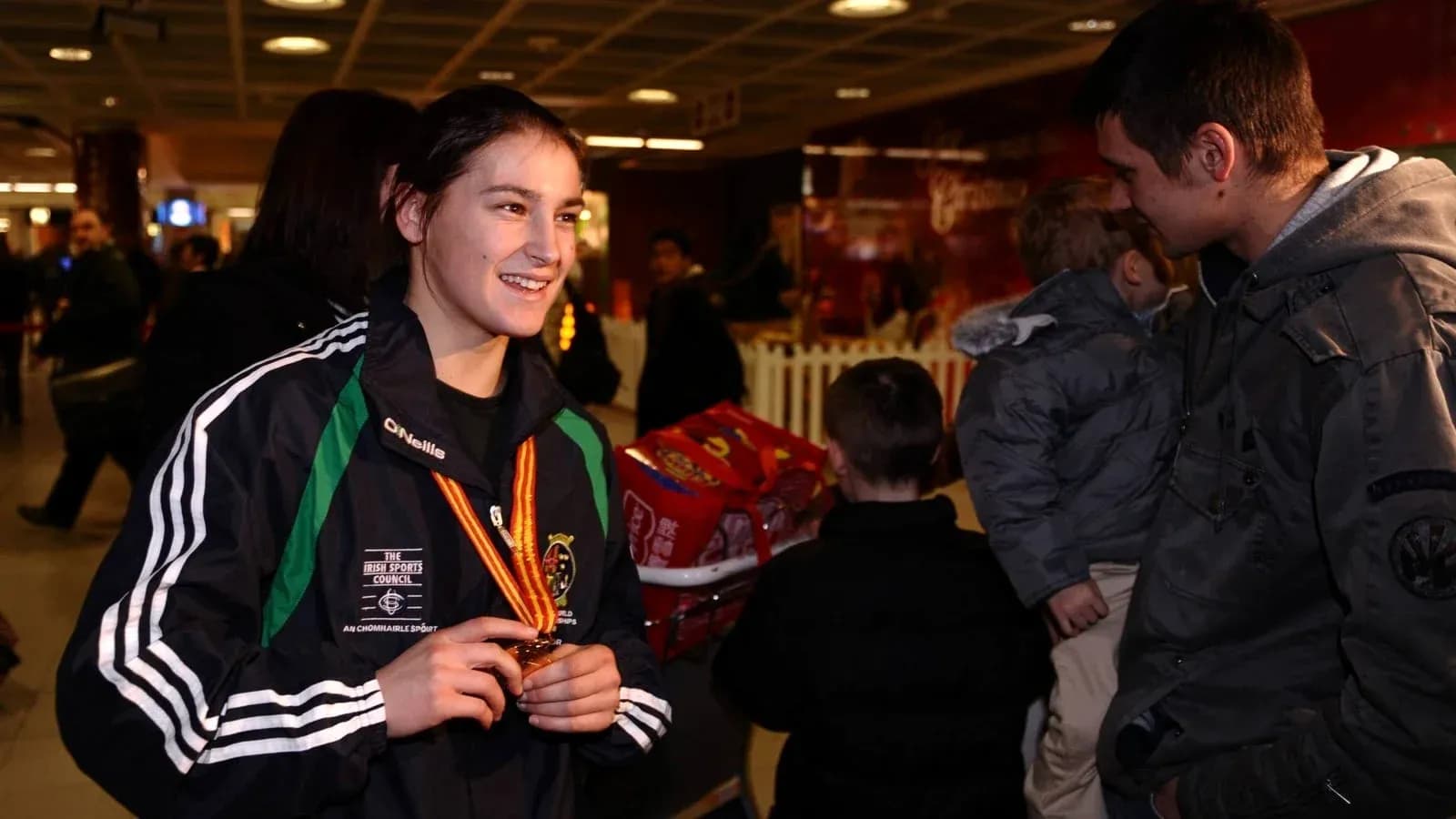 Athlete holding medal at airport with fans