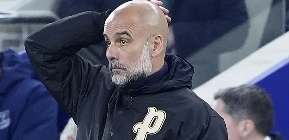 Bald coach with hand on head during match