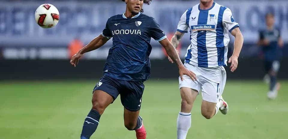 Player in blue jersey dribbling past opponent in white jersey