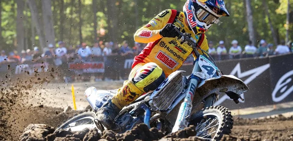 Motocross rider racing on dirt track with spectators