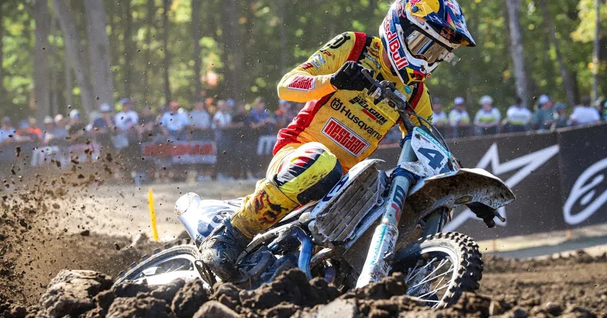 Motocross rider racing on dirt track with spectators