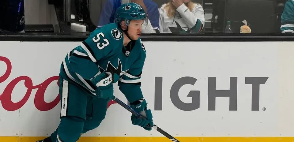 Hockey player in teal jersey skating on ice