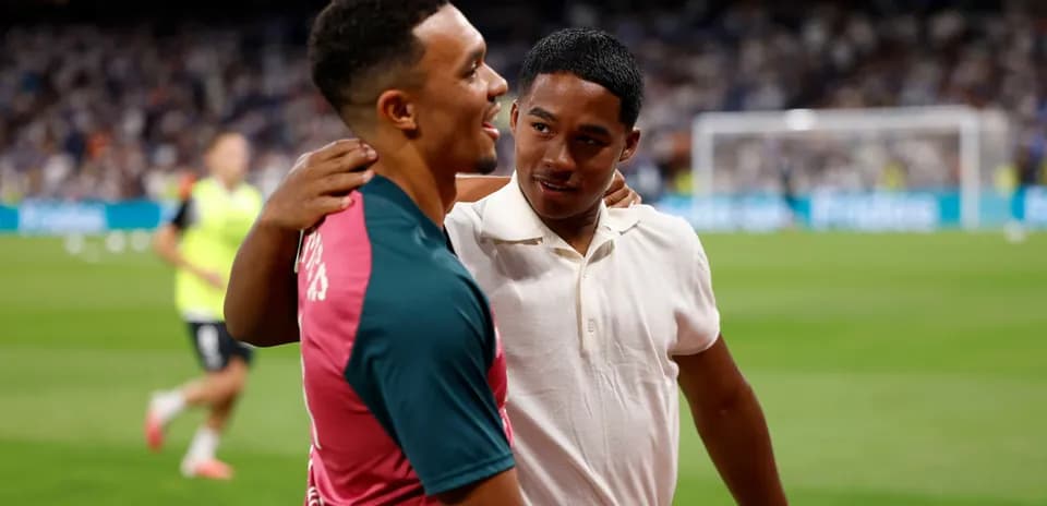 Two young men embracing on a football pitch