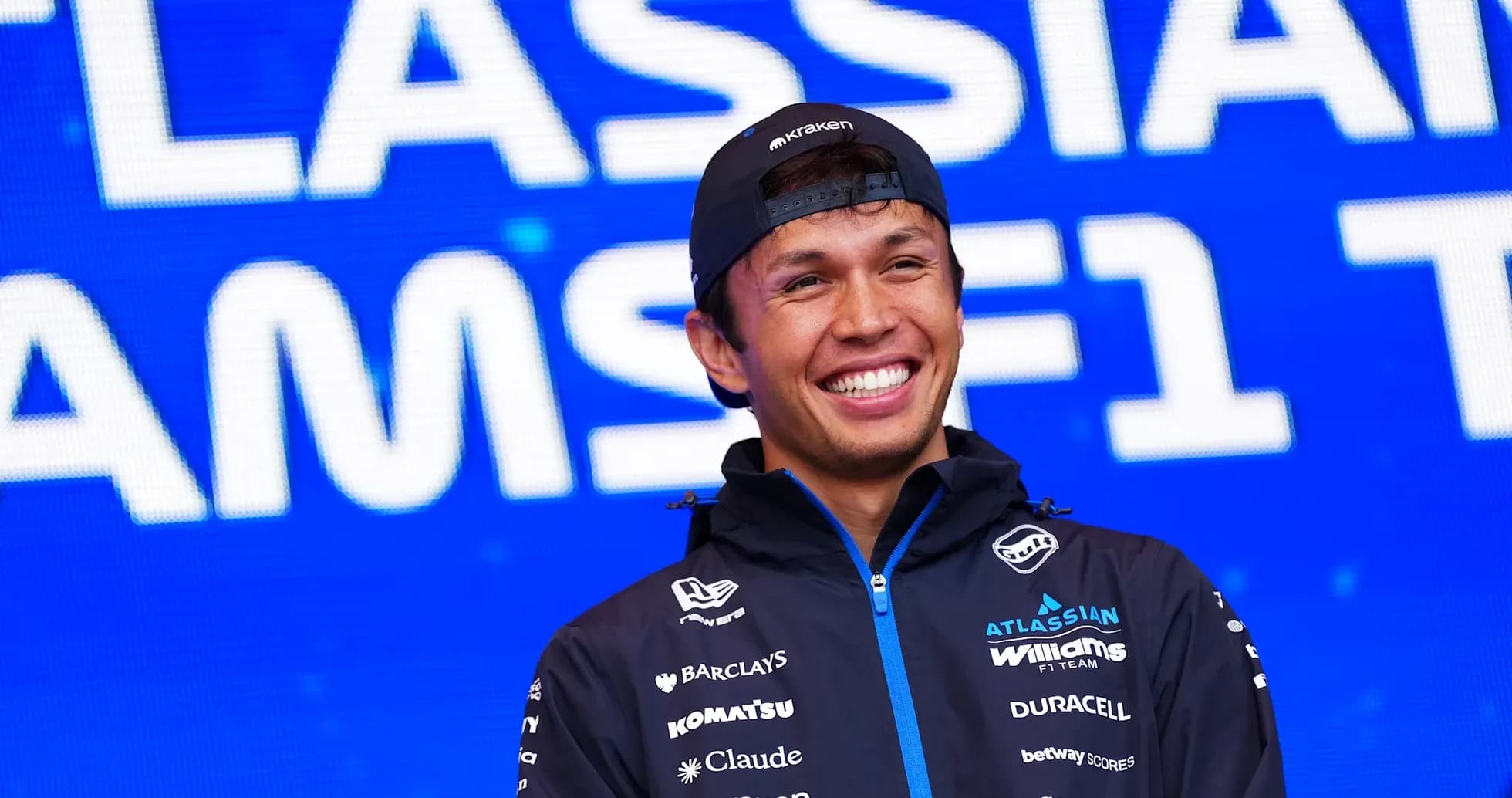 F1 driver smiling during team event backdrop