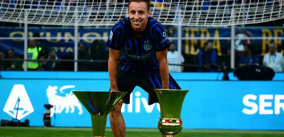 Futbolchi ikki kubok bilan maydonda turgan