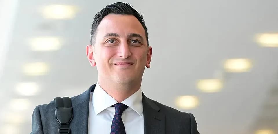 Man in suit smiling with a shoulder bag
