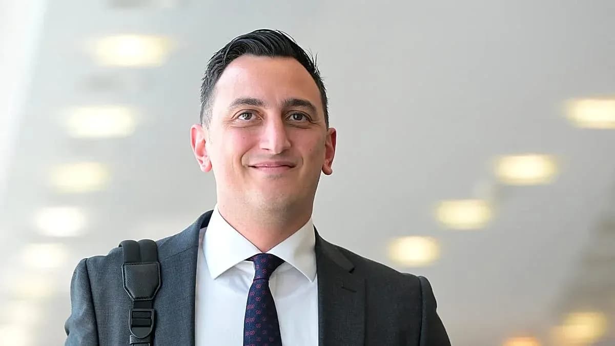 Man in suit smiling with a shoulder bag