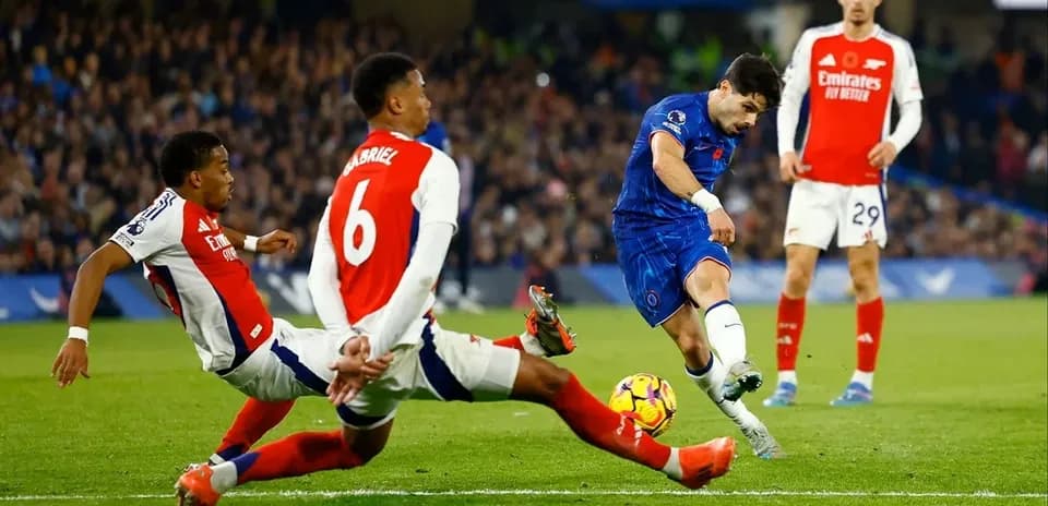 Chelsea player shooting while Arsenal defenders challenge
