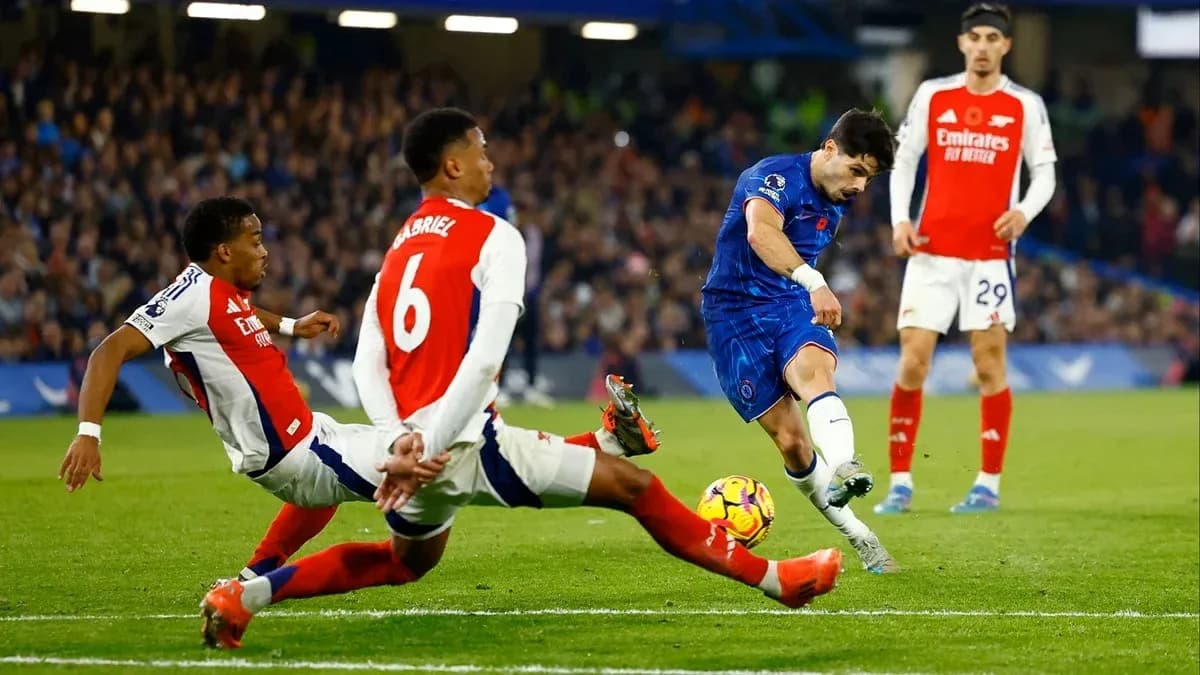 Chelsea player shooting while Arsenal defenders challenge