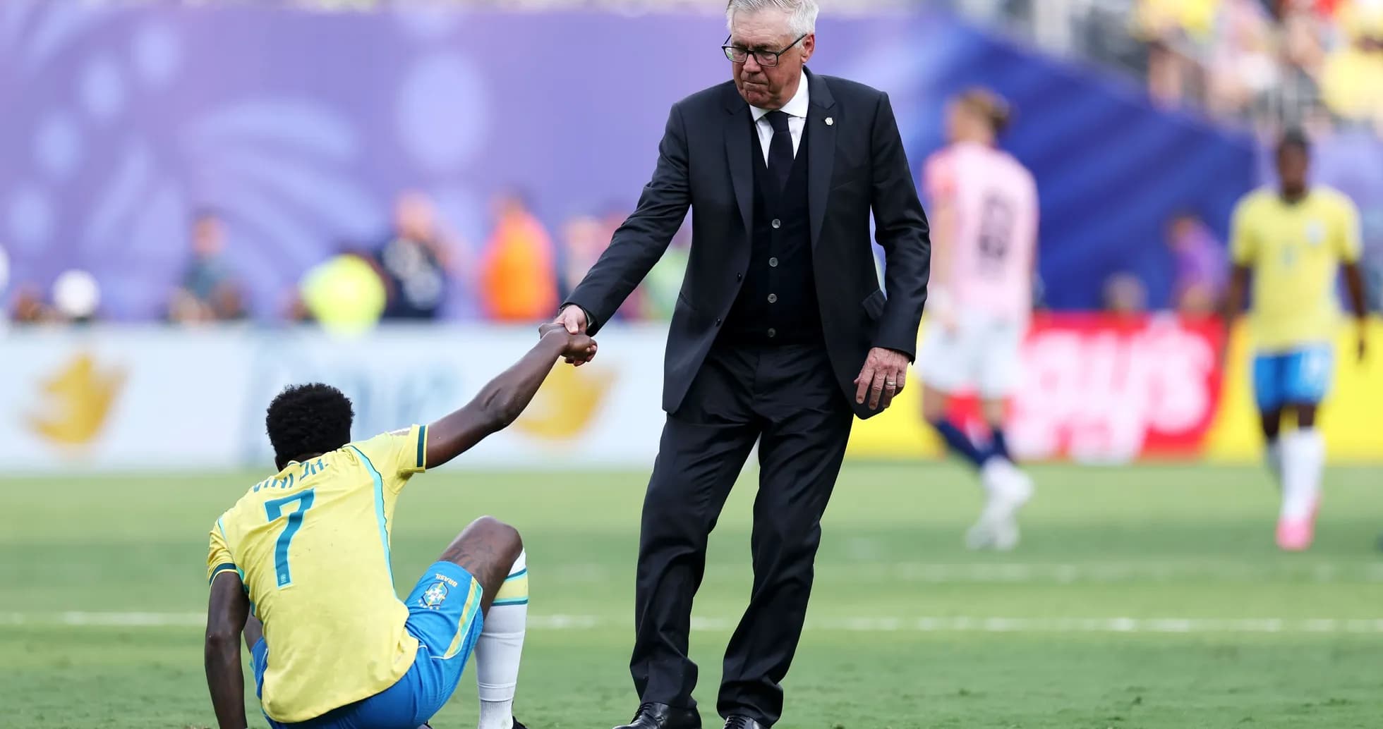 Coach helping player up during match on field