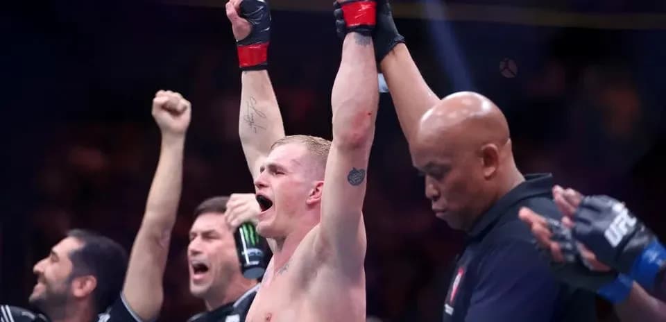 Fighter celebrating victory with raised arms in ring