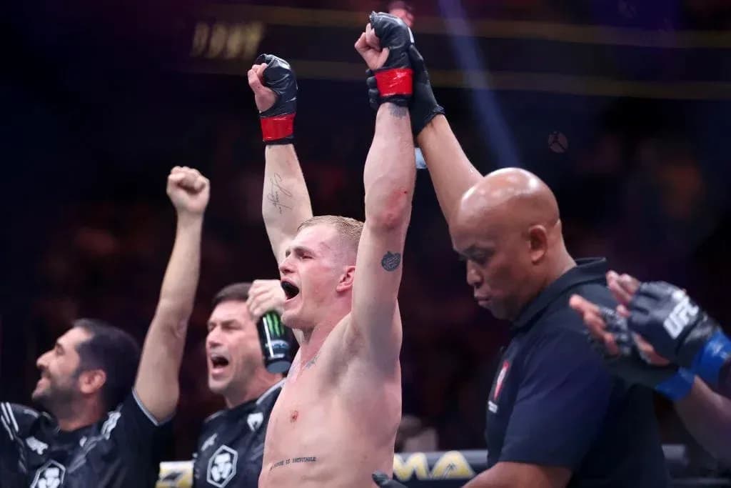 Fighter celebrating victory with raised arms in ring