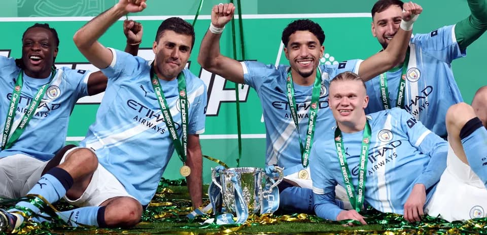 Manchester City players celebrating with trophy and medals