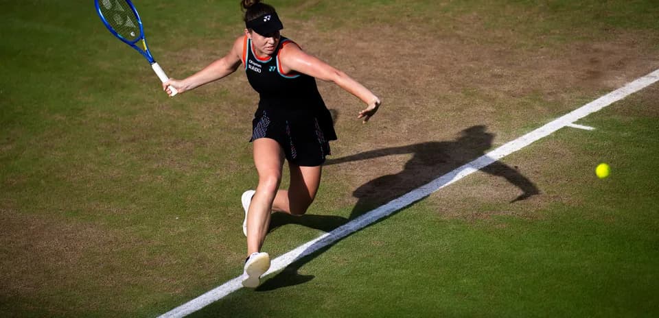 Tennis player returning a shot on grass court