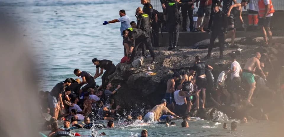 People struggling in water near rocky shore
