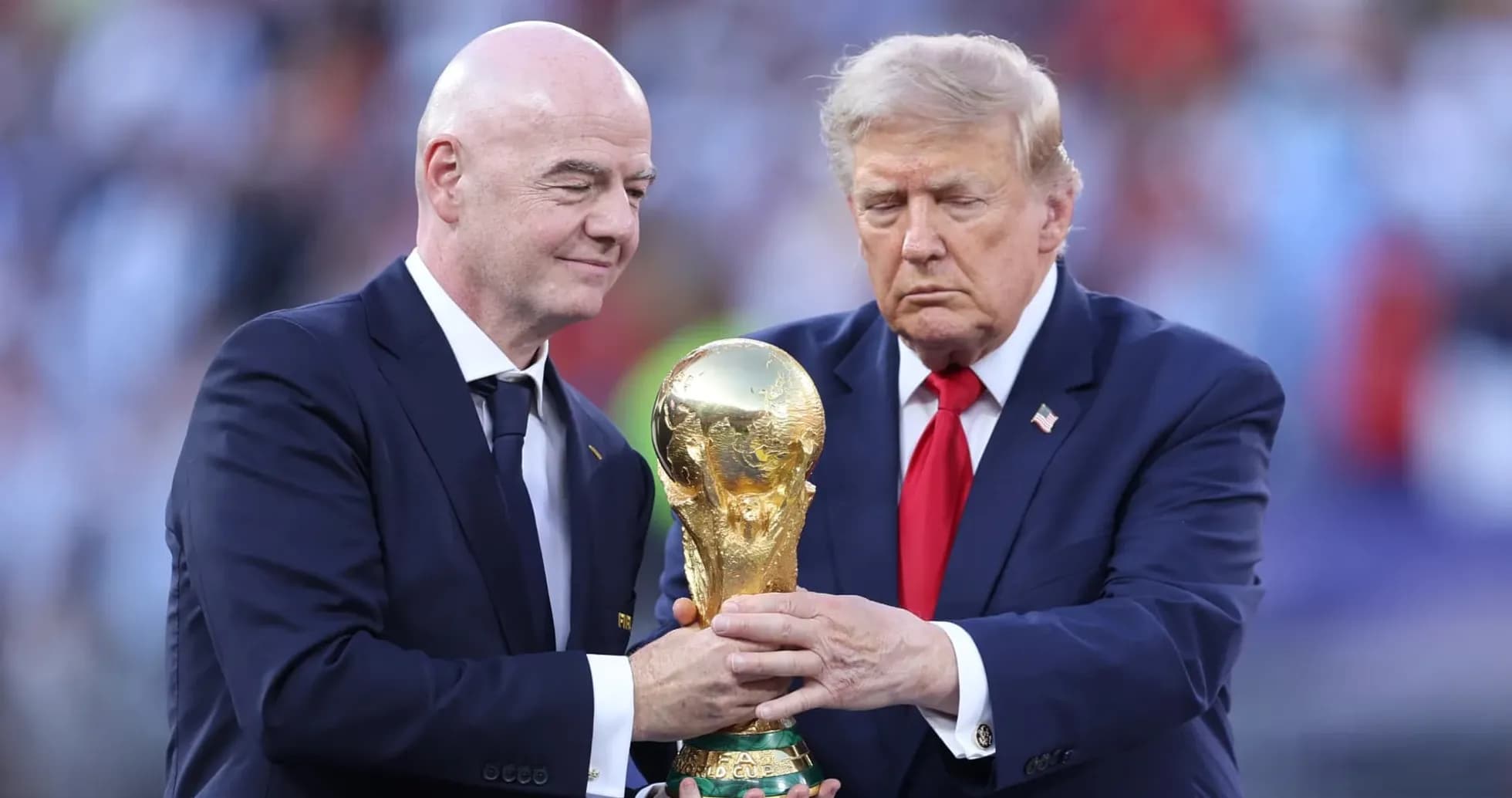 Two men holding FIFA World Cup trophy on stage