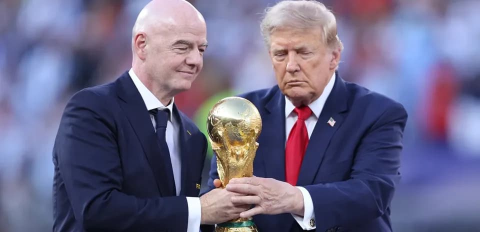 Two men holding FIFA World Cup trophy on stage