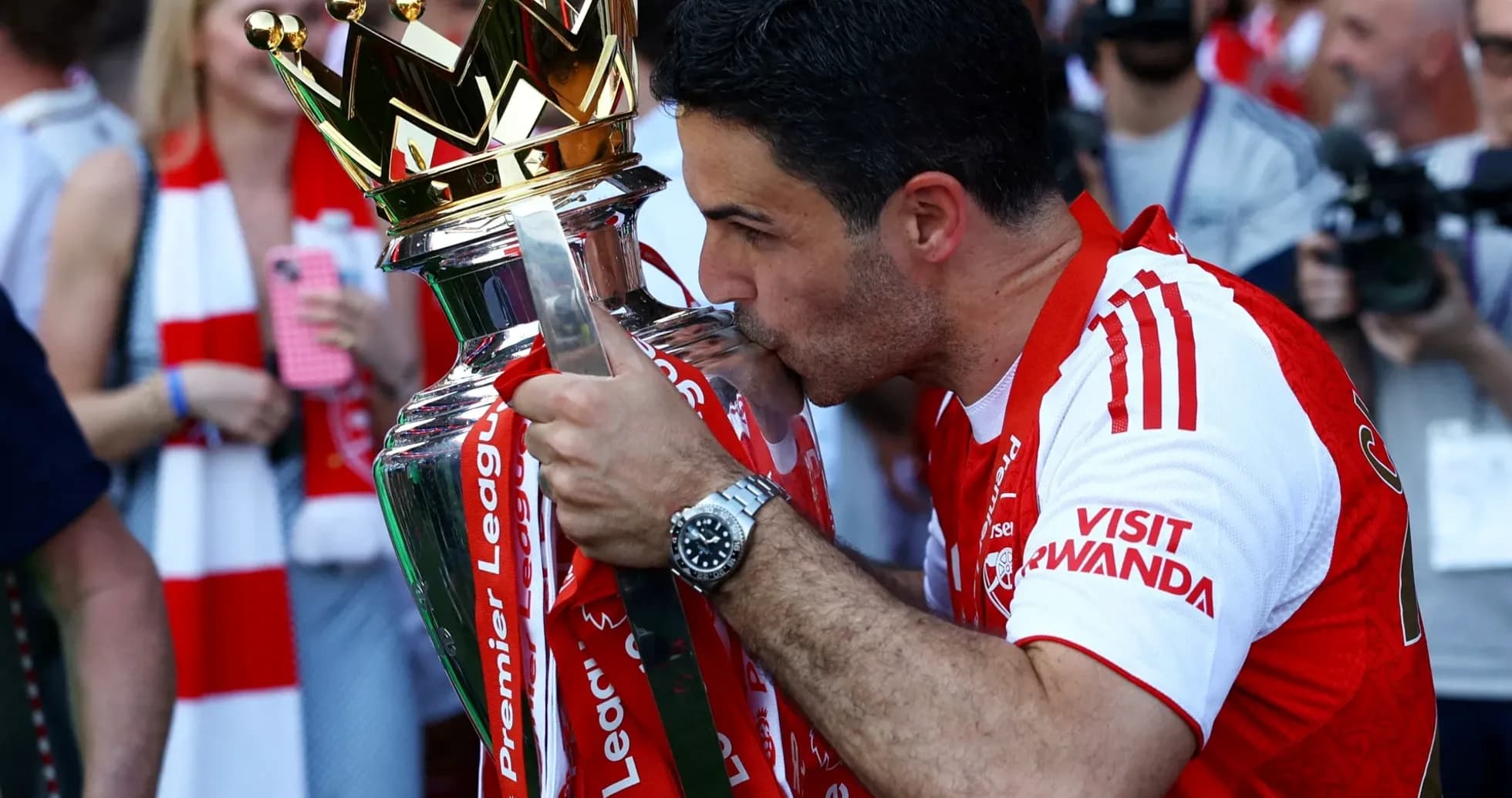 Mikel Arteta kissing Premier League trophy on stage