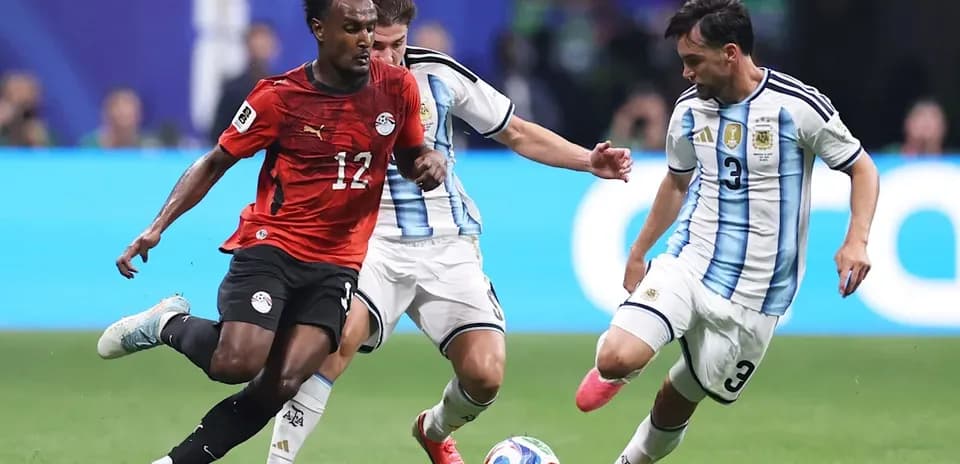 Egyptian player dribbling past Argentine defenders during match