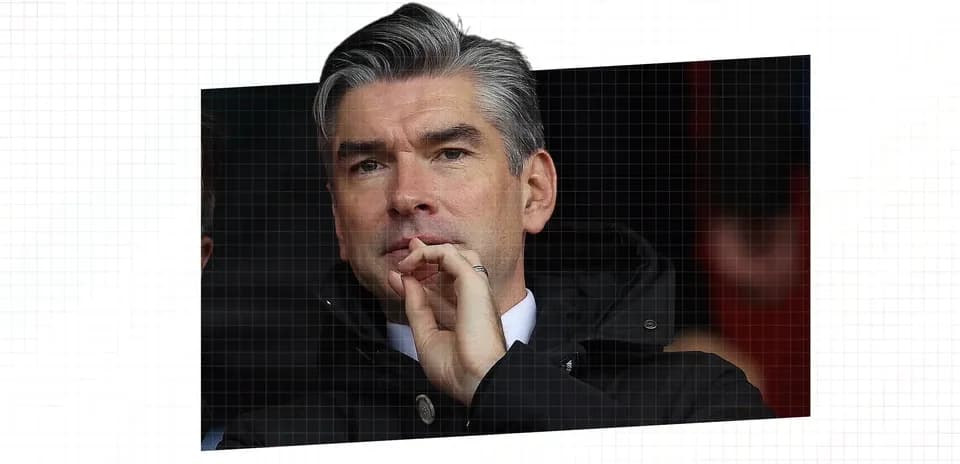 Man in coat observing match from the stands