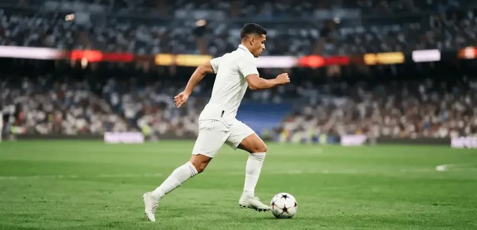 Futbolchi to'p bilan yugurmoqda