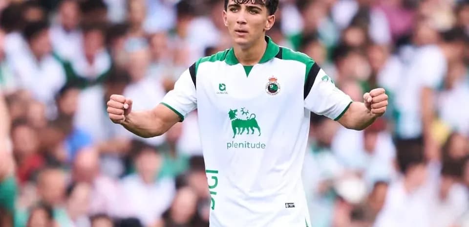 Futbolchi maydonda qo'lini ko'tarib turibdi