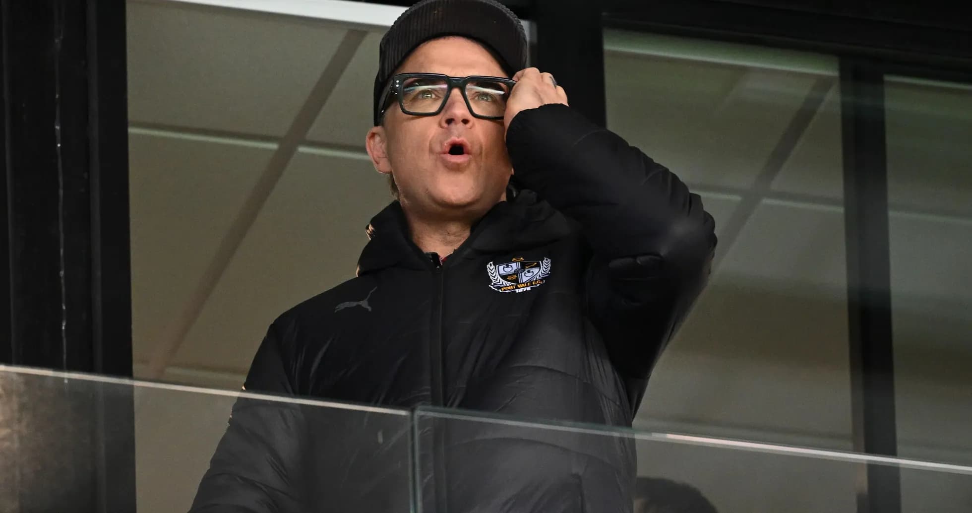 Man in a black jacket shouting from a balcony