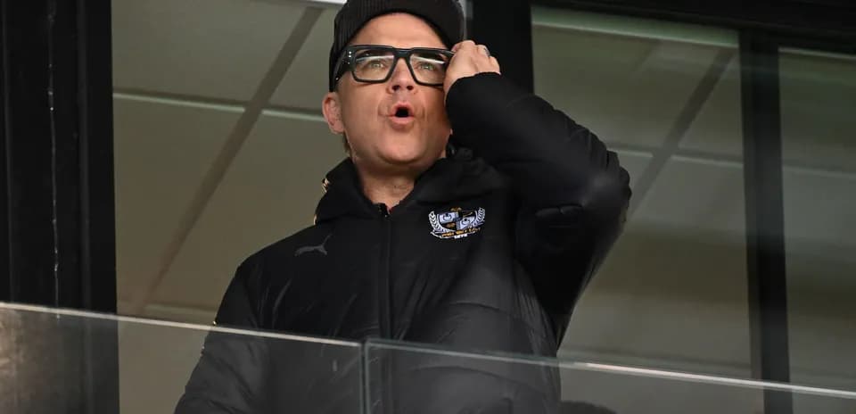 Man in a black jacket shouting from a balcony