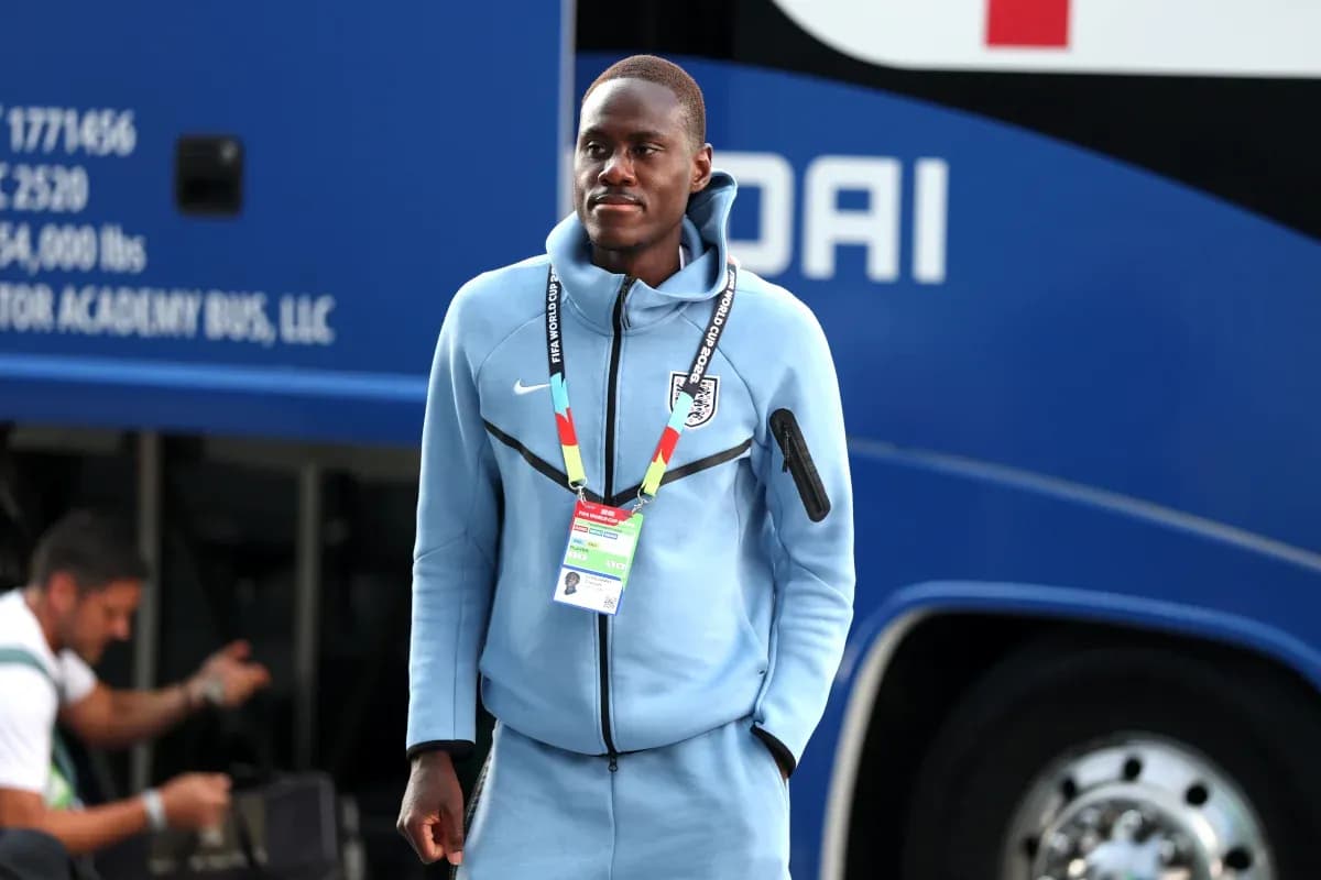 Futbolchi avtobus oldida ko'k kiyimda turibdi