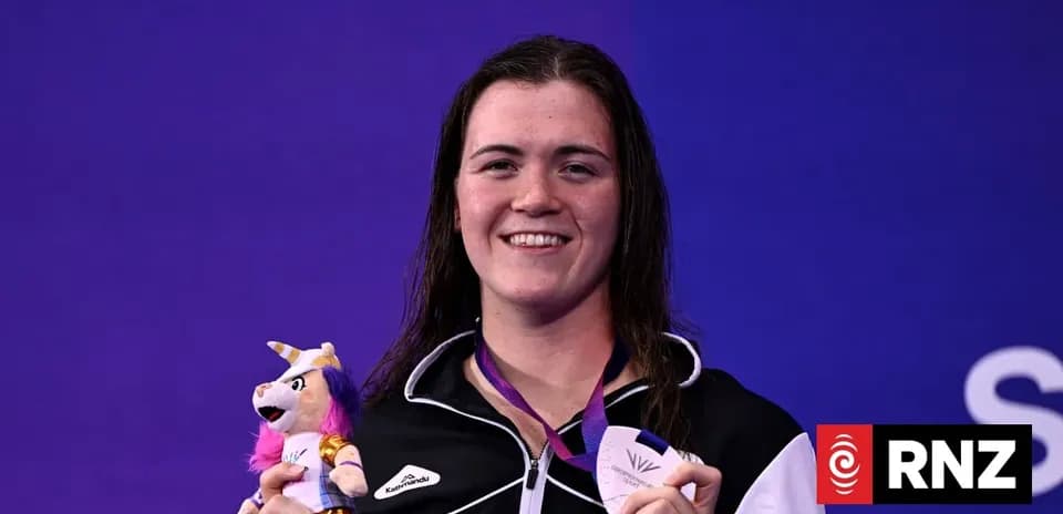 Sportsperson holding medal and plush toy at event