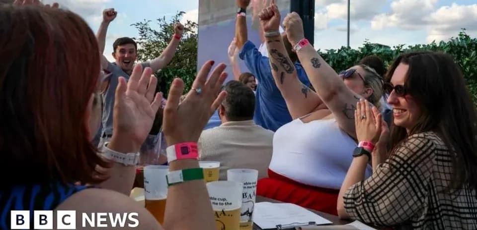 People celebrating with raised hands at outdoor event