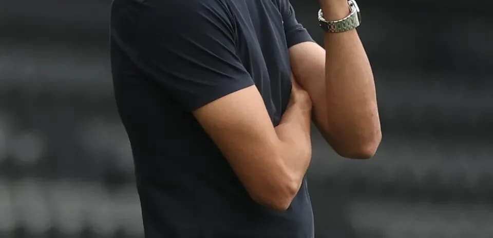 Coach observing match with arms crossed