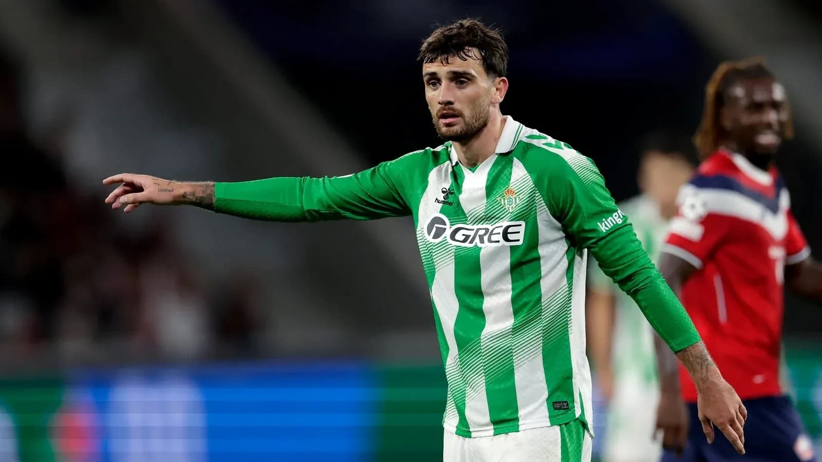 Futbolchi maydonda qo'lini ko'tarib ko'rsatmoqda